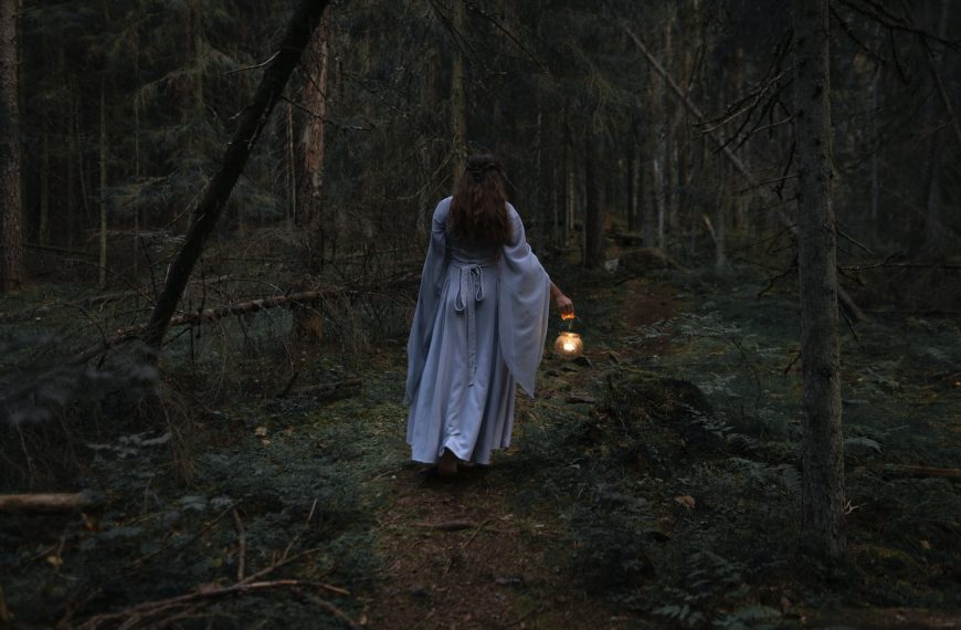 a woman dressed as a ghost walking through a forest